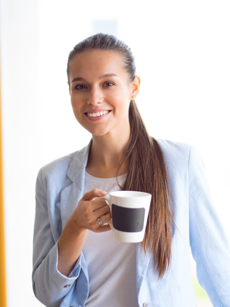 Aantrekkelijke vrouw achter balie in kantoor met afhaalmaaltijden koffie. - Foto, afbeelding