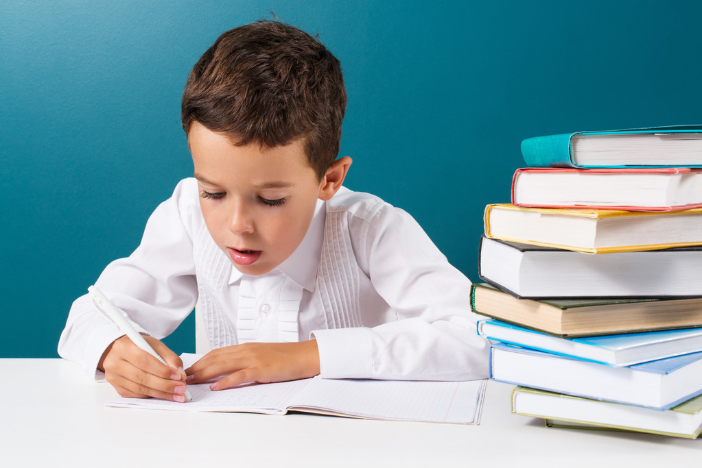 Pensive cute boy with homework sitting at a table - Photo, Image