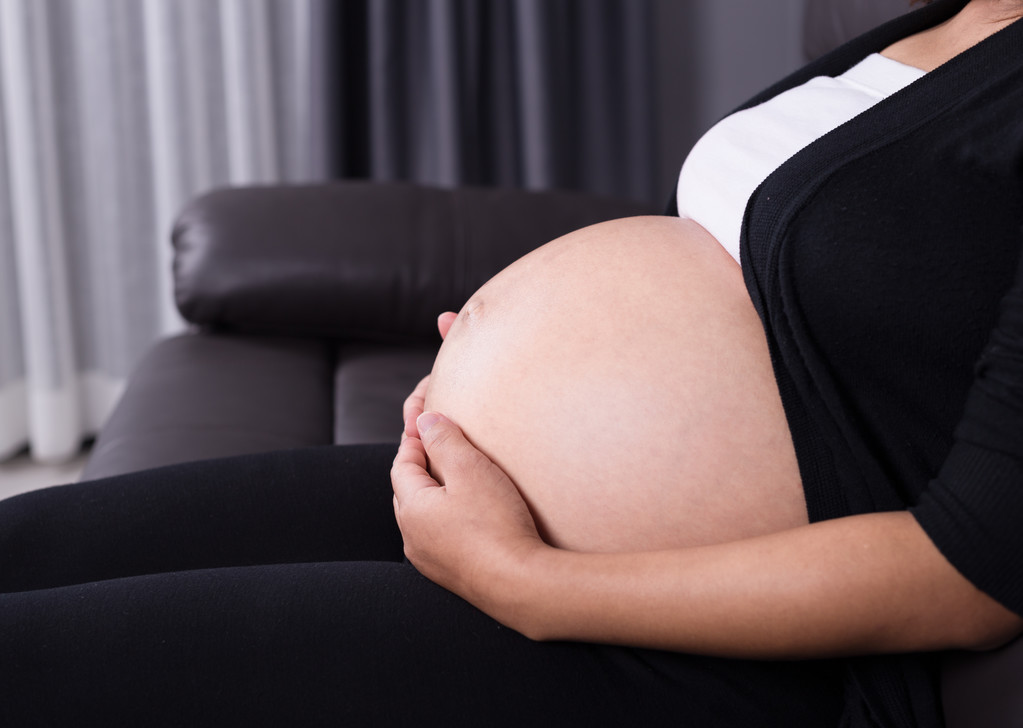 Bauch einer schwangeren Frau auf dem Sofa - Foto, Bild