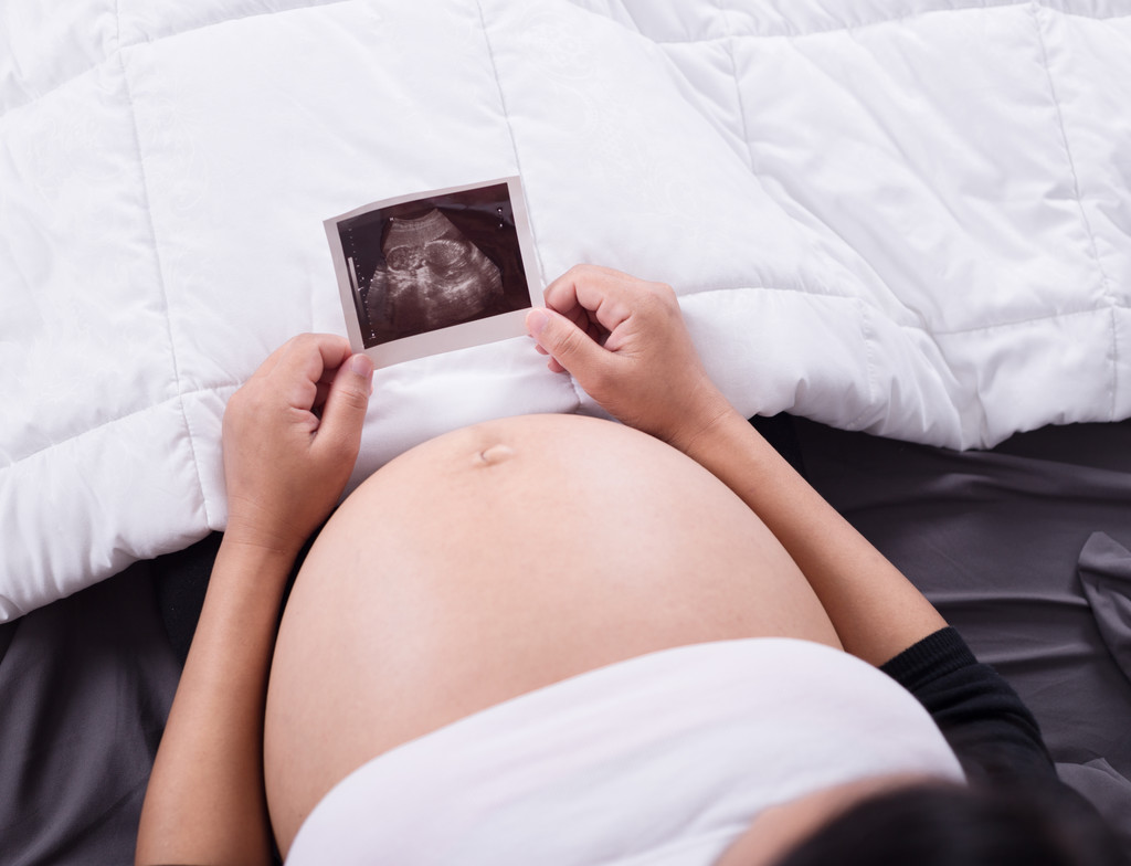 b yatakta oturup bebek ultrason görüntüsü ile hamile kadın - Fotoğraf, Görsel