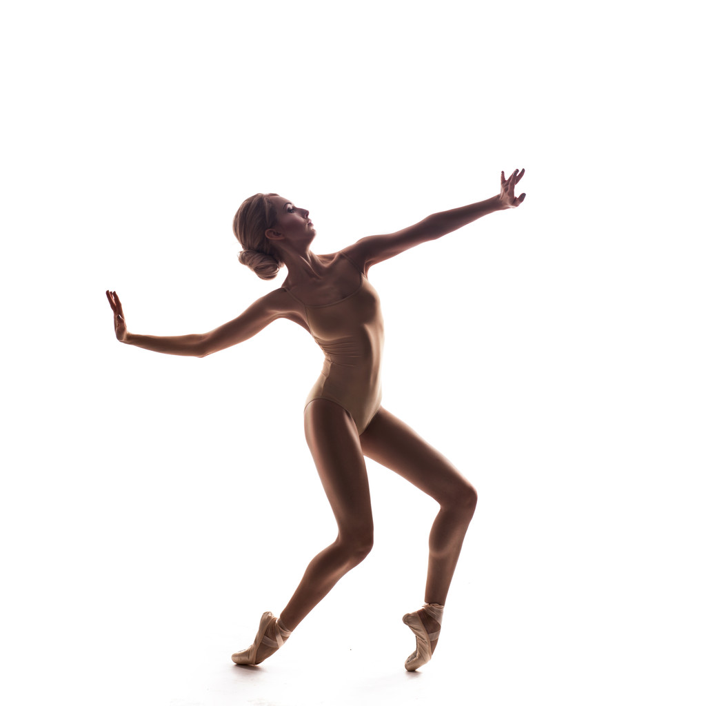 Балерина в бежевом наряде позирует на пальцах ног
 - Фото, изображение