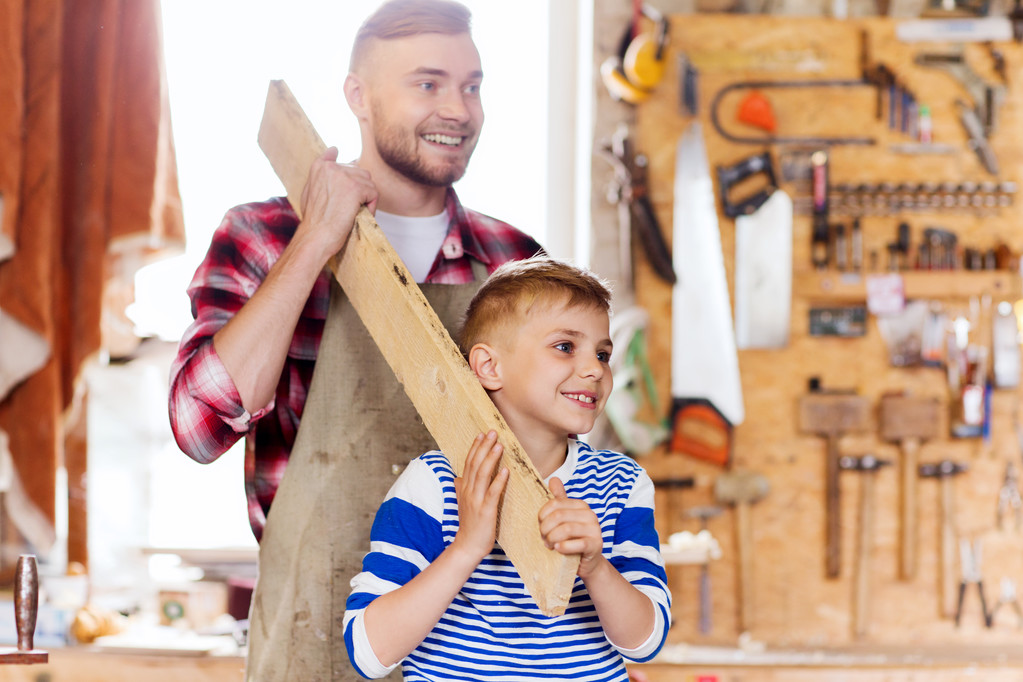 happy father and son with wood plank at workshop - Photo, Image