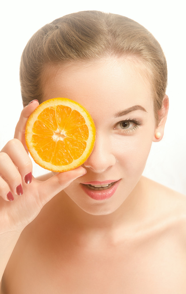 Młoda kobieta uśmiechający się z plasterkiem pomarańczy - Zdjęcie, obraz