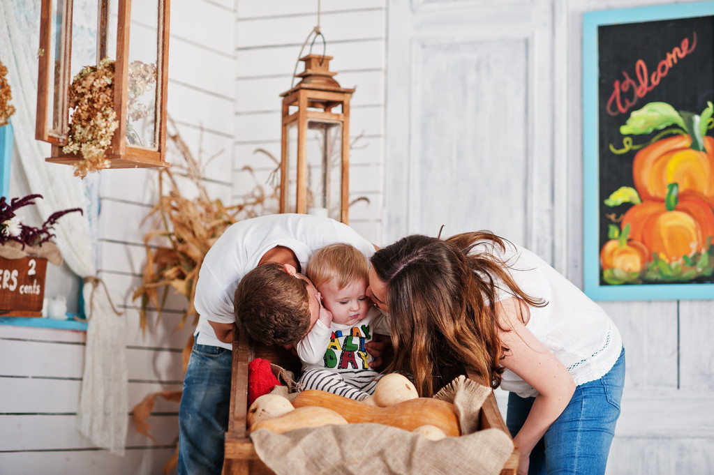 Молода кавказька щаслива сім'я в любові на фоні білого дерев'яного роу
 - Фото, зображення