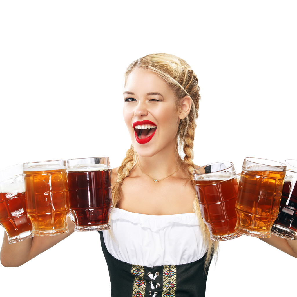 Молодая сексуальная Октоберфест официантка, одетая в традиционное баварское платье, подающая большие кружки пива изолированные на белом фоне
. - Фото, изображение