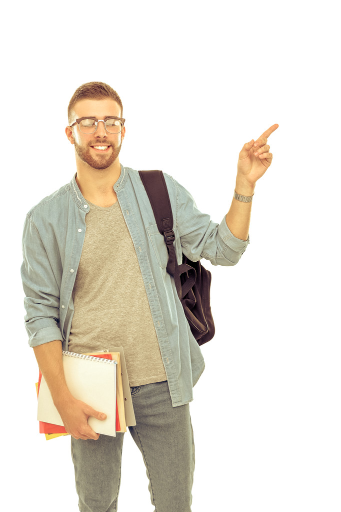 Um estudante do sexo masculino com um saco escolar segurando livros e apontando isolado em fundo branco
 - Foto, Imagem