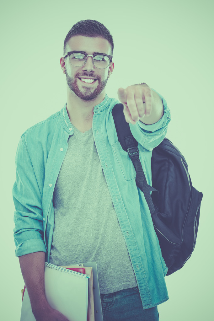 ein männlicher Schüler mit einer Schultasche, die Bücher hält und einen isoliert auf weißem Hintergrund zeigt - Foto, Bild