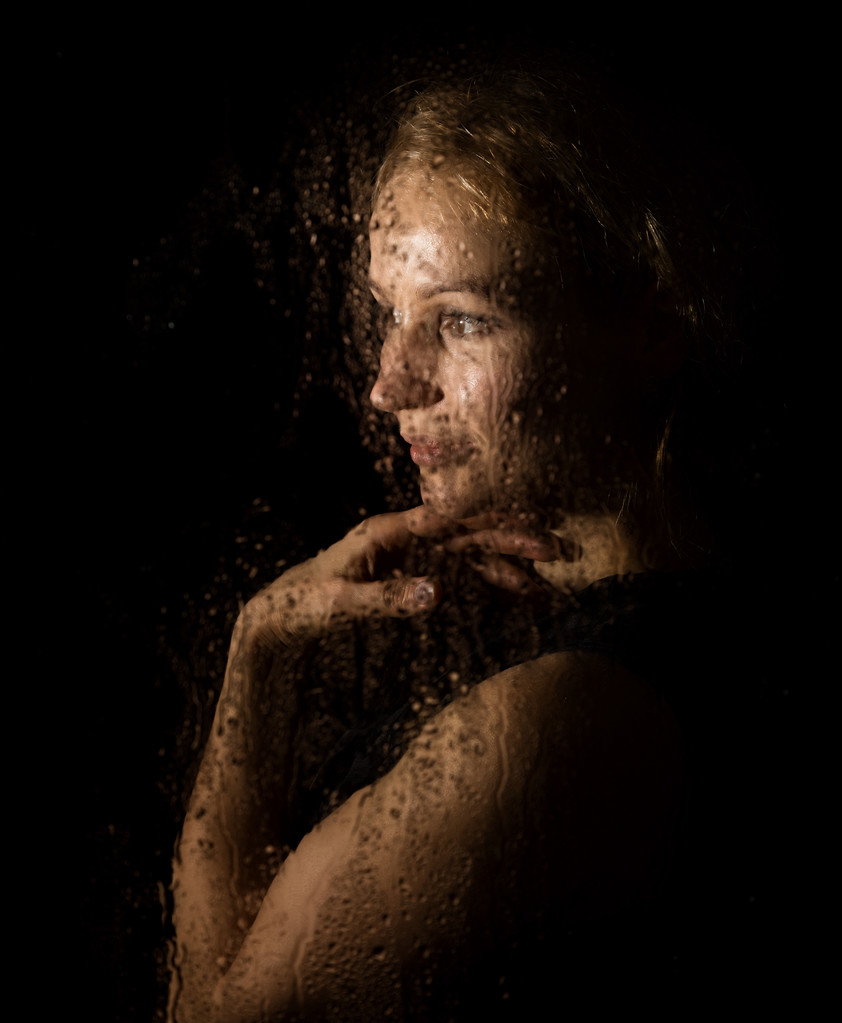 Płynne portret seksowna model/ka, pozowanie za przezroczyste szkło pokryte przez krople wody. - Zdjęcie, obraz