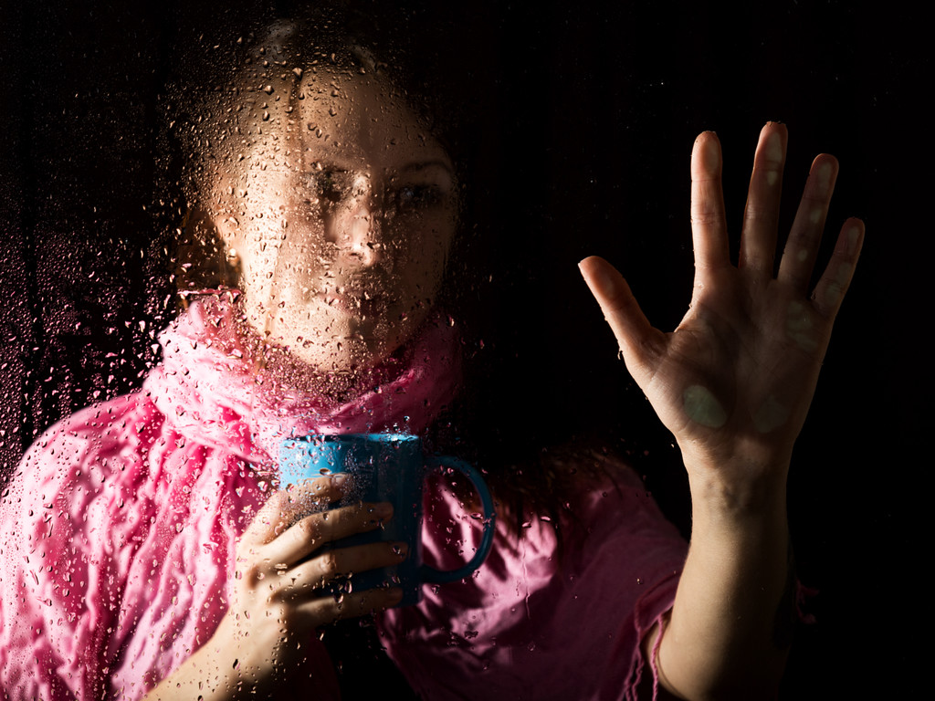 Portret młodej kobiety sad za oknem deszcz deszcz spada na niego. Dziewczyna trzyma na filiżankę gorącego napoju - Zdjęcie, obraz