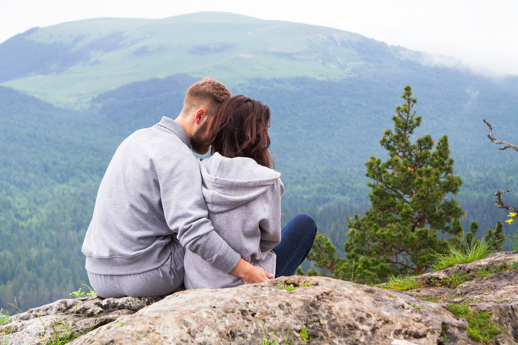 Loving young hipster couple sitting on a mountain, hugging and l - Photo, Image