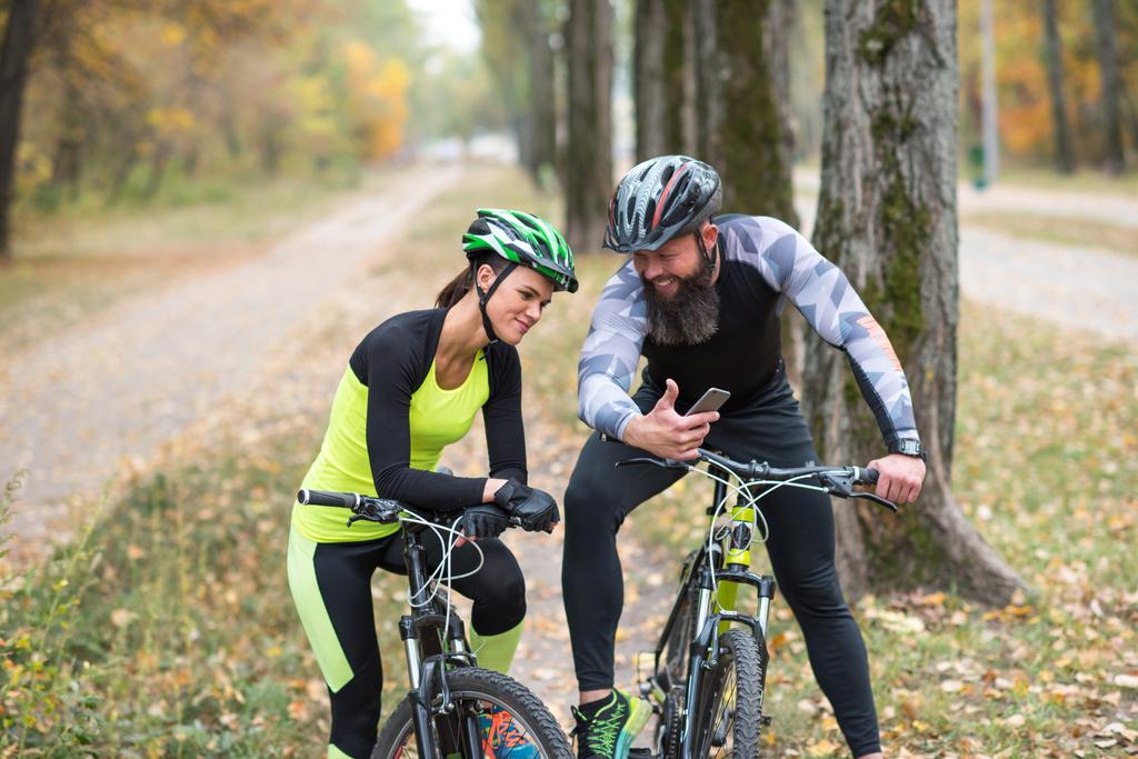 человек велосипедист показать смартфон девушке
  - Фото, изображение