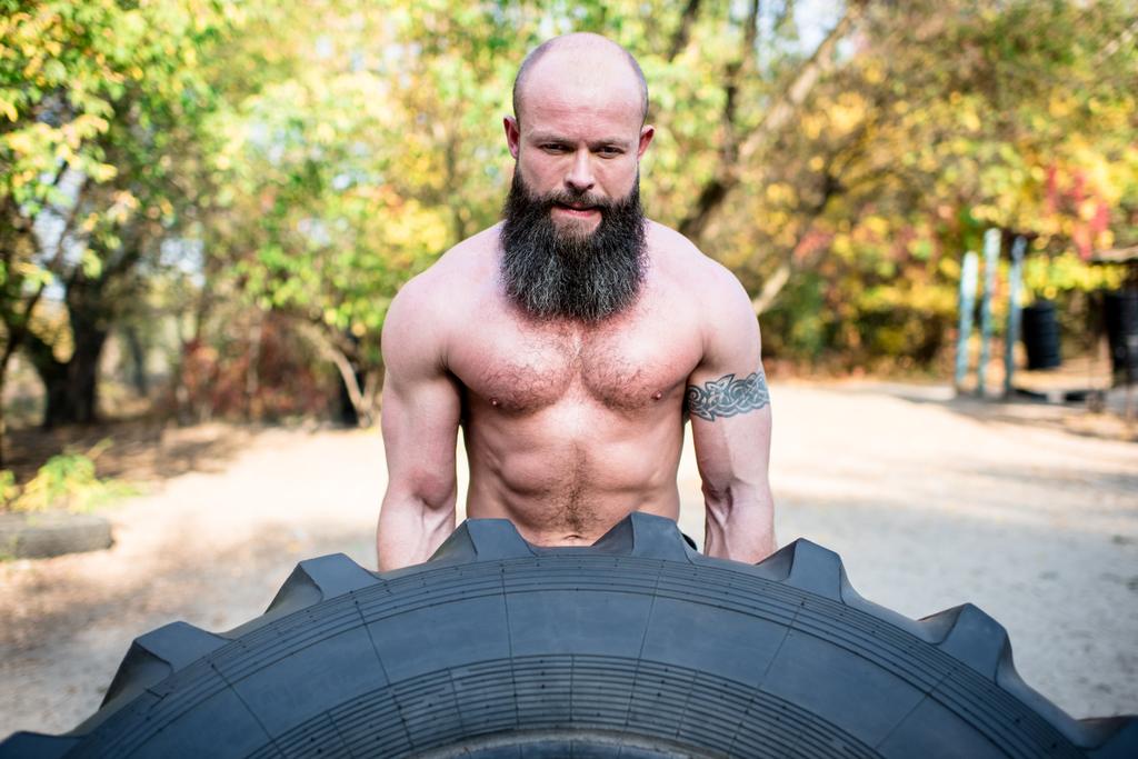 Man lifting a large tractor tire  - Photo, Image