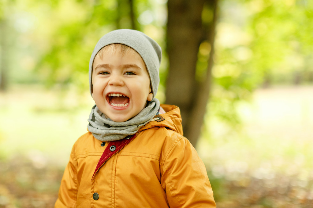 Маленький очаровательный мальчик в желтой куртке улыбается осенью
 - Фото, изображение