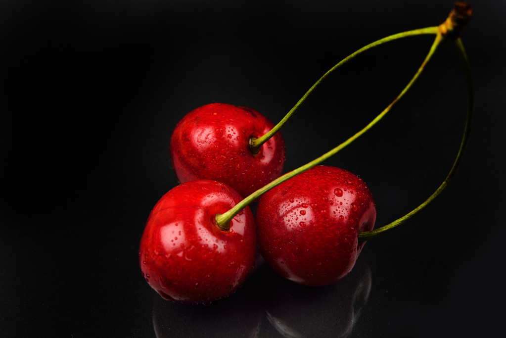 Две красные вишни и одна разбилась о отражающую черную спину
 - Фото, изображение