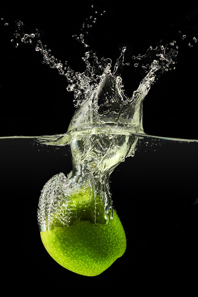 Pomme verte tombant dans l'eau sur fond noir
 - Photo, image