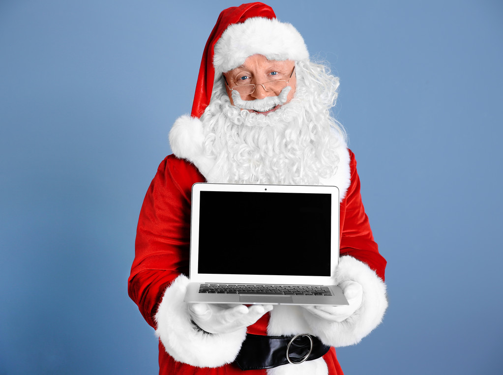 Santa Claus holding laptop on blue background - Fotografie, Obrázek