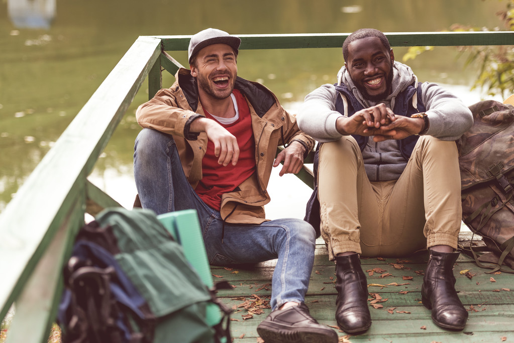 Usmívající se muži s batohy sedět na molu - Fotografie, Obrázek