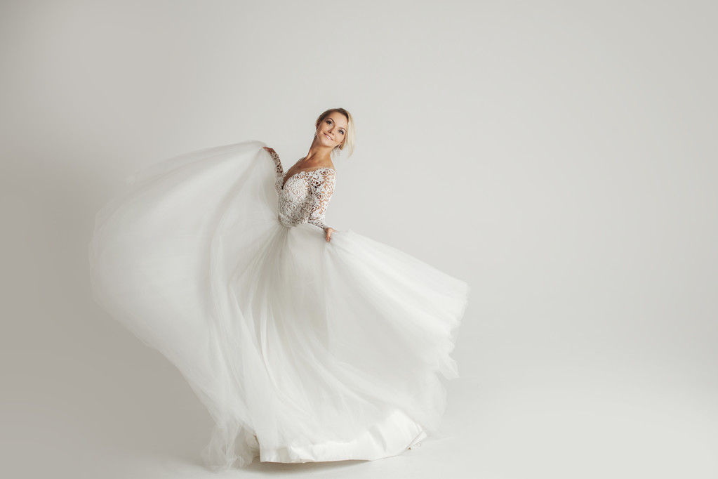 Belle mariée attrayante en robe de mariée avec jupe longue pleine, fond blanc, danse et sourire
 - Photo, image
