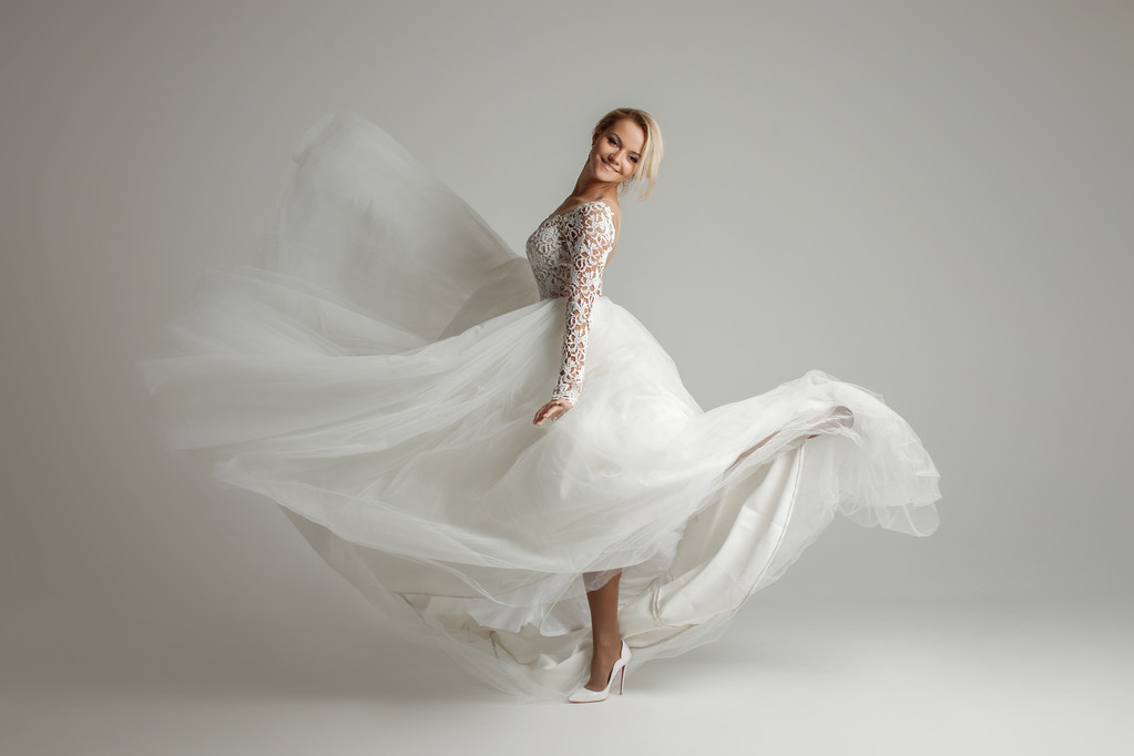 Belle mariée attrayante en robe de mariée avec jupe longue pleine, fond blanc, danse et sourire
 - Photo, image