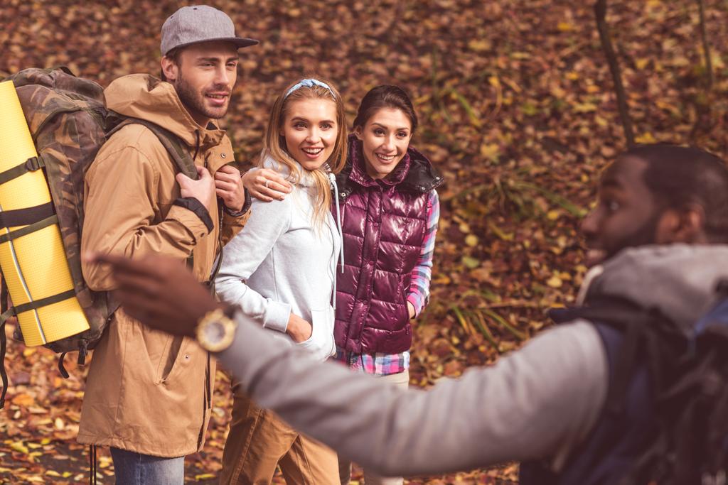 Smiling man with friends in autumn forest - Photo, Image