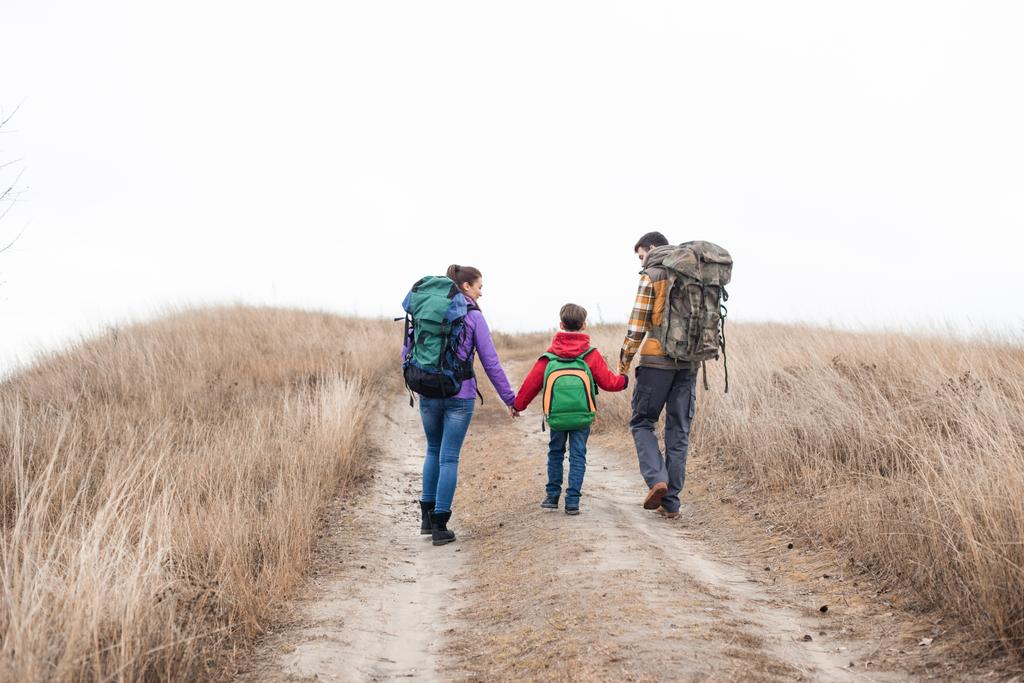 Familie mit Rucksack auf ländlichem Weg unterwegs - Foto, Bild