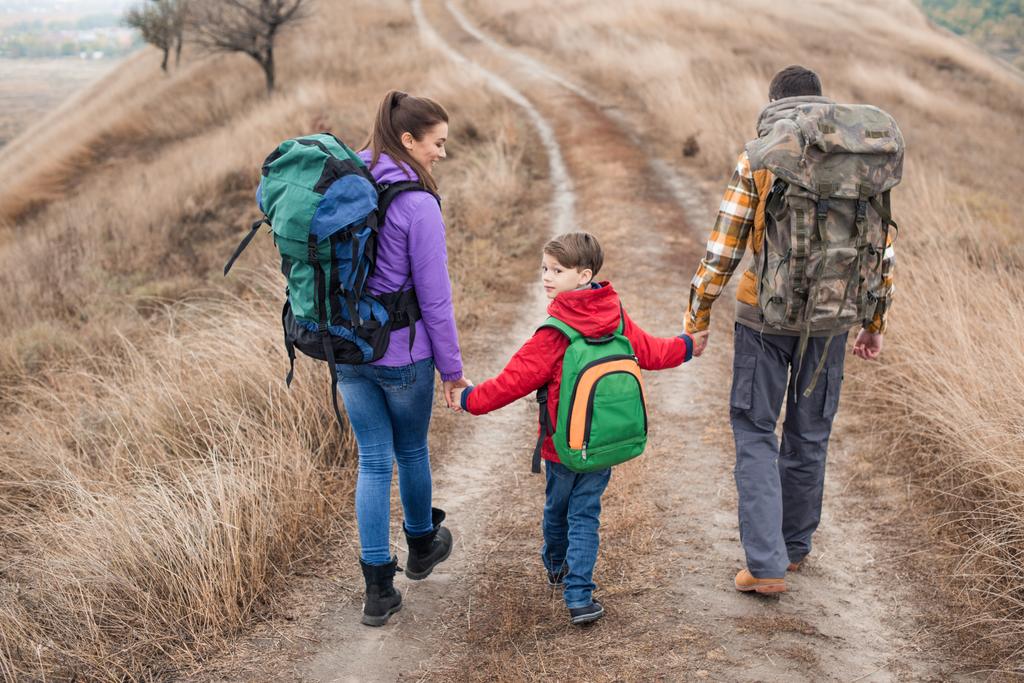Family with backpacks walking on rural path - 写真・画像