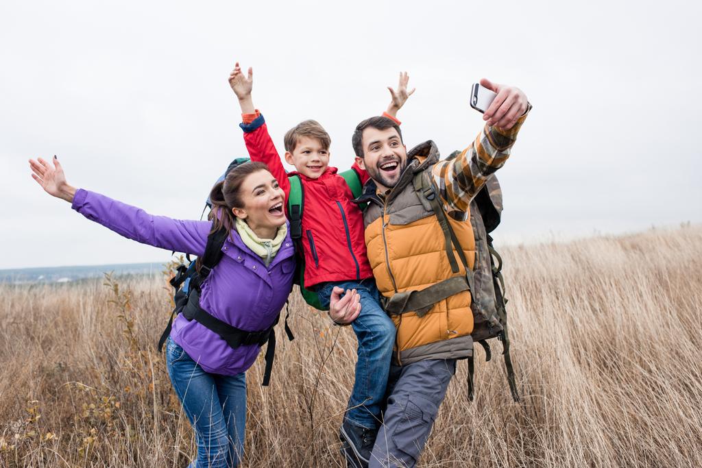 Família feliz com mochilas tirando selfie
 - Foto, Imagem