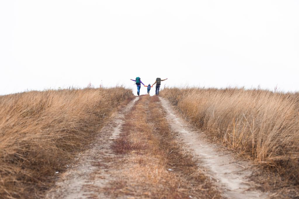 Family with backpacks running on rural path - Fotografie, Obrázek