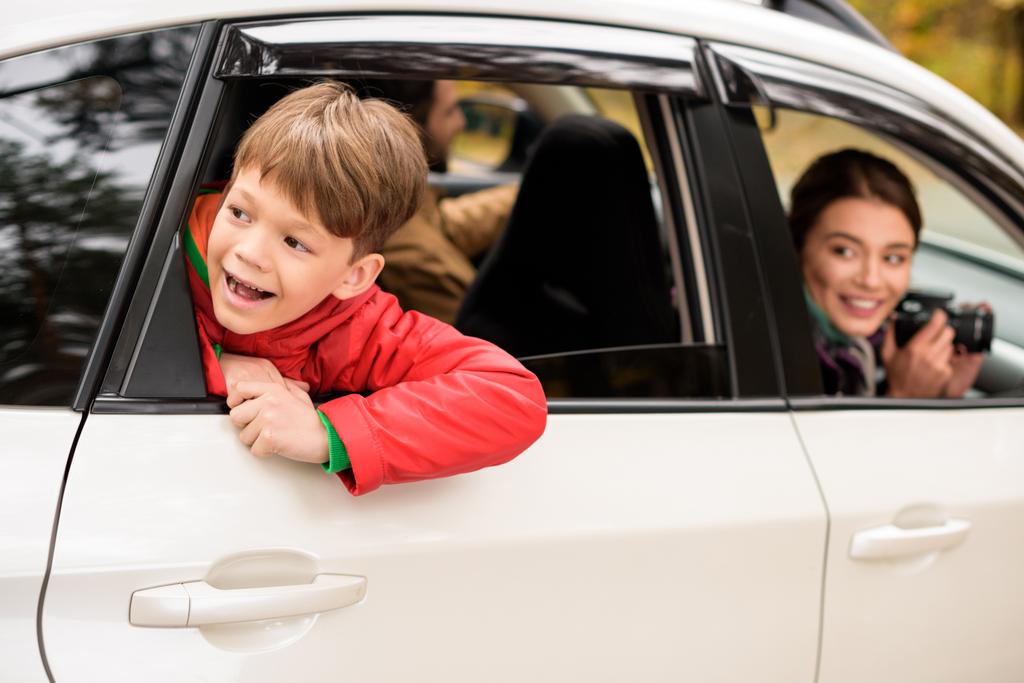Uśmiechnięty chłopiec patrząc przez okno samochodu - Zdjęcie, obraz