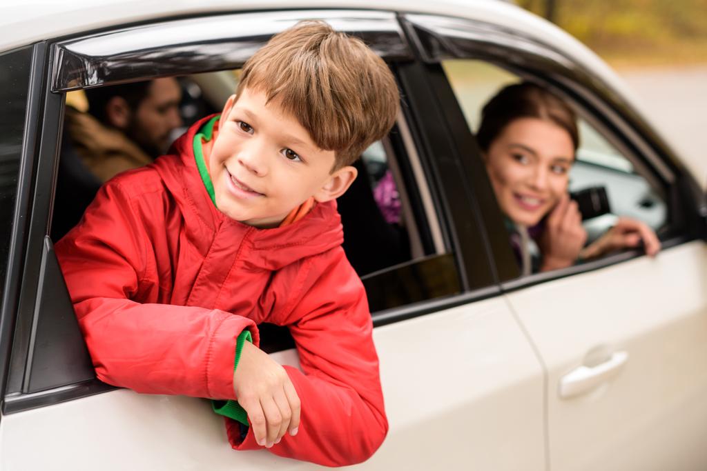 Uśmiechnięty chłopiec patrząc przez okno samochodu - Zdjęcie, obraz