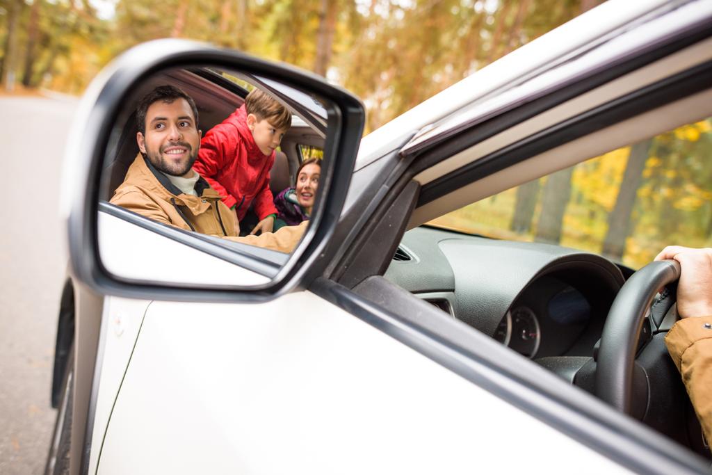 Onnellinen perhe heijastuu auton peiliin
 - Valokuva, kuva