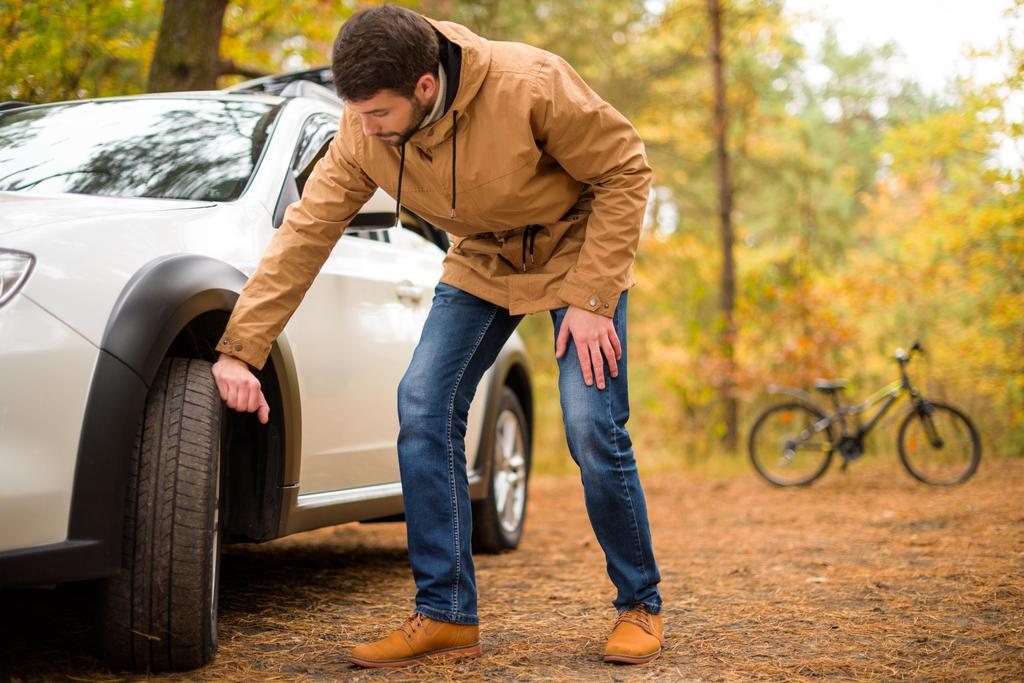 Homem verificando pneu de carro
  - Foto, Imagem