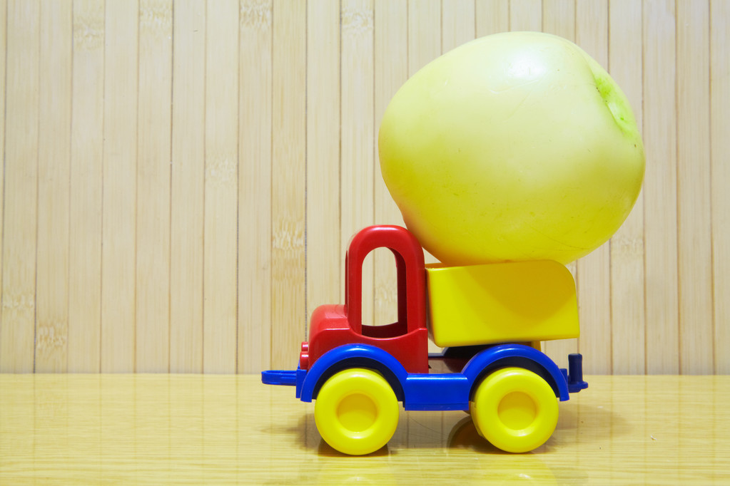 Kunststof speelgoedauto met groene appel - Foto, afbeelding