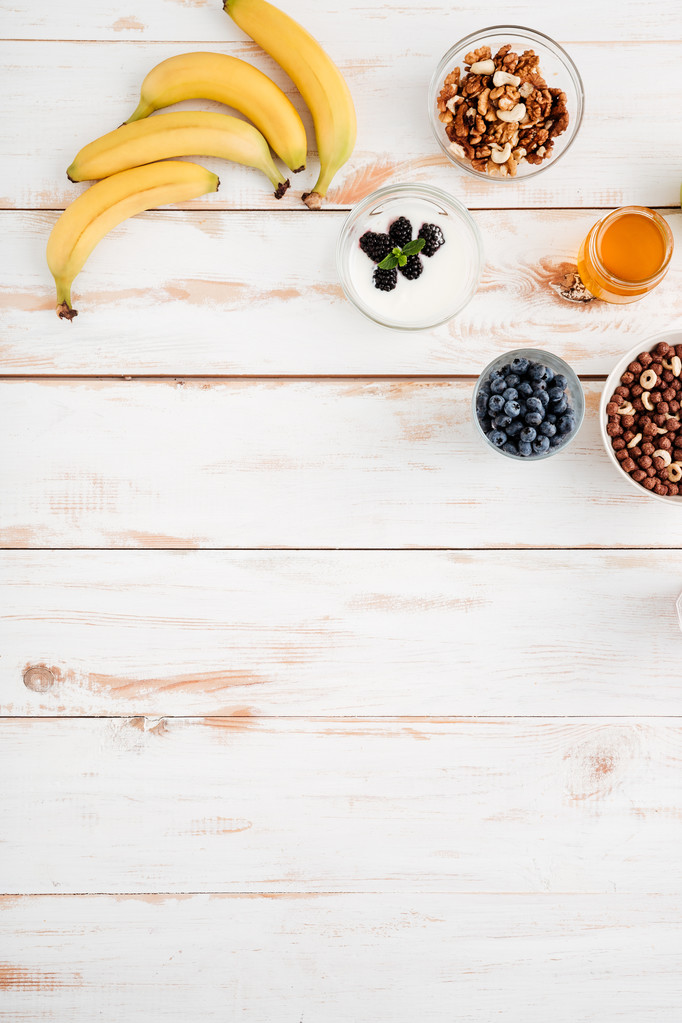 Bananas, berries, walnuts and honey on wooden background - Photo, Image