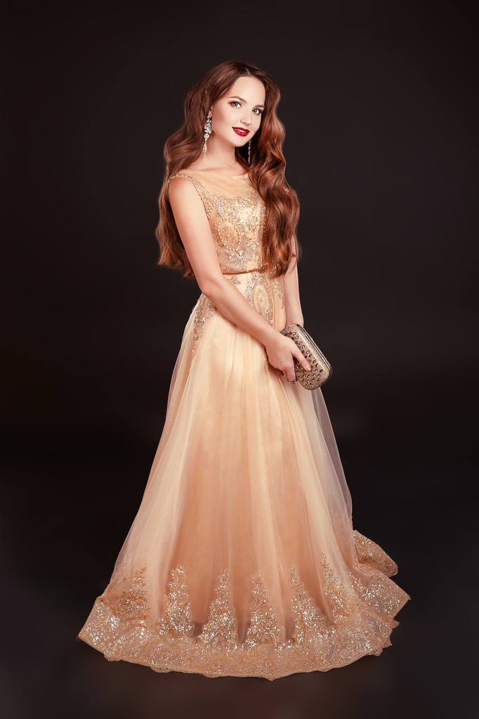 Beautiful brunette woman posing in long golden dress isolated on - 写真・画像