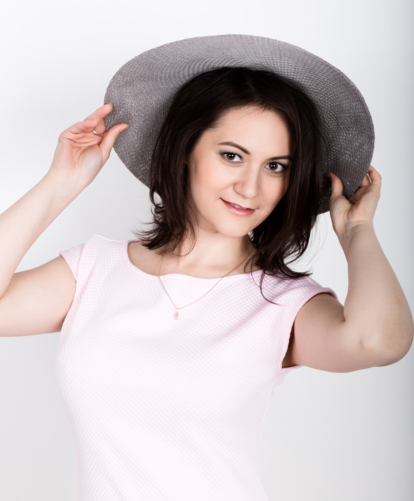 όμορφη νεαρή μελαχρινή γυναίκα κρατώντας ένα ευρείας γείσο καπέλο, αυτή έκφραση των διαφόρων συναισθημάτων - Φωτογραφία, εικόνα