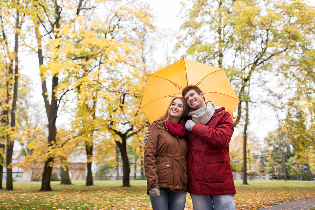 smiling couple with umbrella in autumn park - Photo, Image
