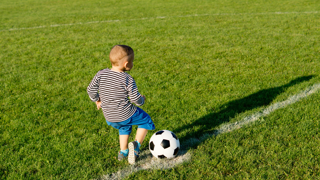 Маленький мальчик пинает футбольный мяч
 - Фото, изображение