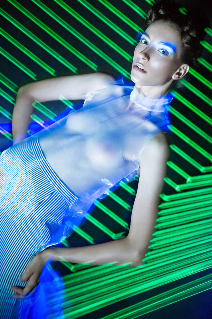 Mannequin mooi meisje in modieuze kleding in ultraviolet licht, tonen verschillende poses. Schoonheid lichaam en gezicht. - Foto, afbeelding