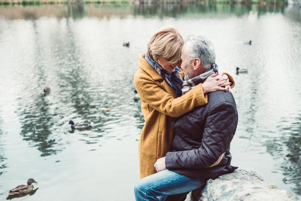 Feliz pareja madura abrazándose cerca del lago
  - Foto, imagen
