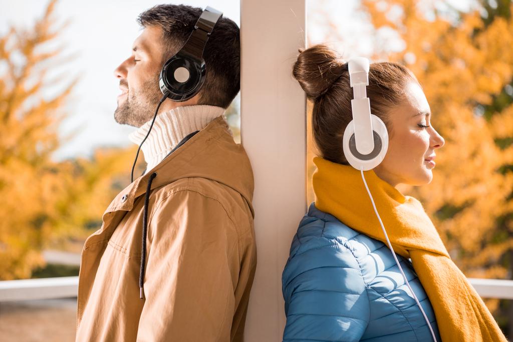 Joven hombre y mujer de pie en los auriculares
 - Foto, Imagen