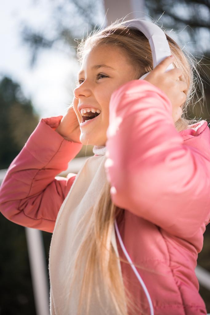 Smiling little girl in white headphones - Photo, Image