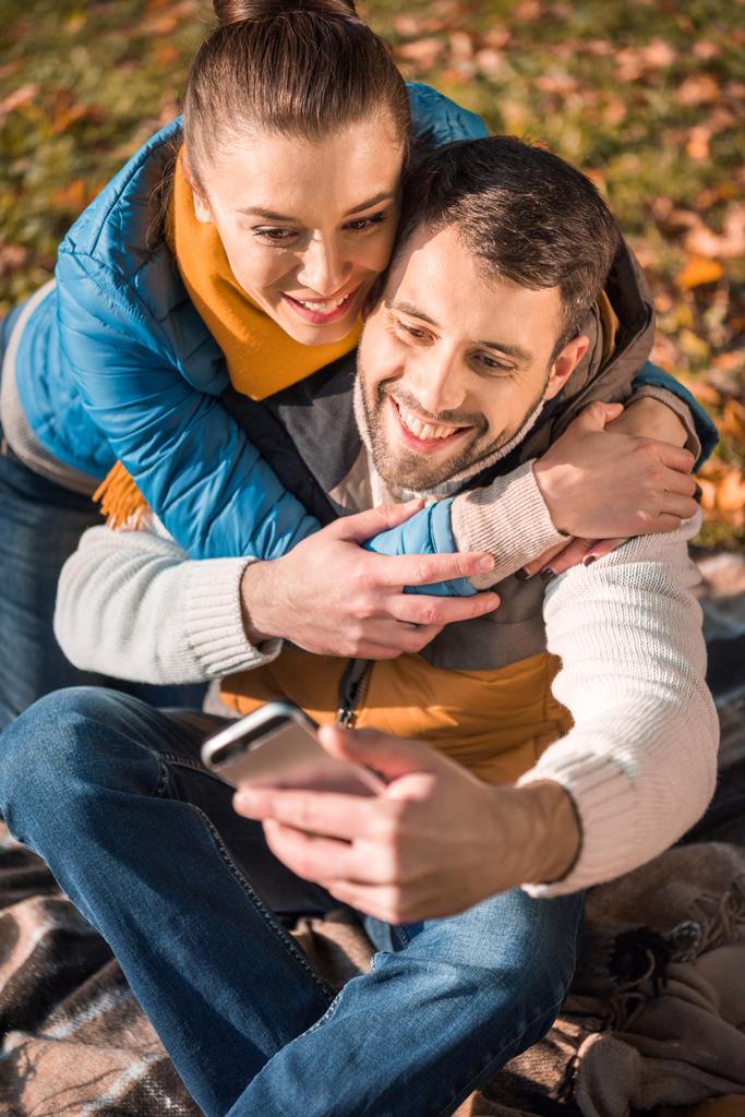 schönes lächelndes Paar schaut aufs Smartphone - Foto, Bild
