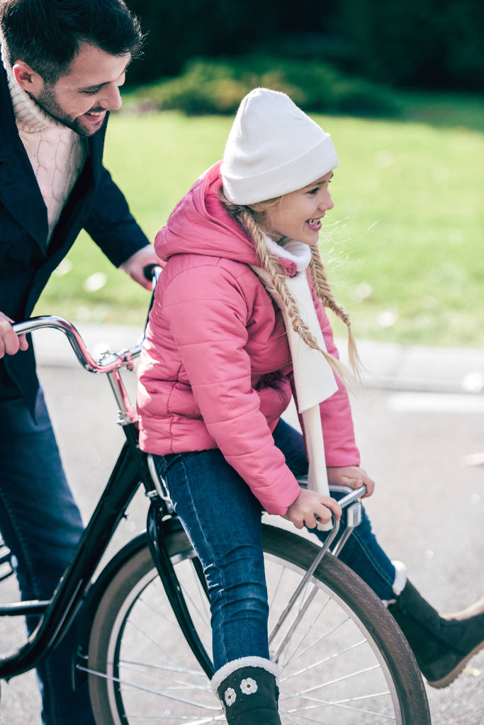 Ο πατέρας ασκεί χαμογελώντας κόρη ποδηλάτων - Φωτογραφία, εικόνα