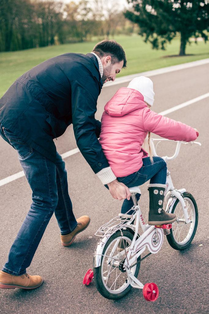 батько вчить дочку їздити на велосипеді
 - Фото, зображення