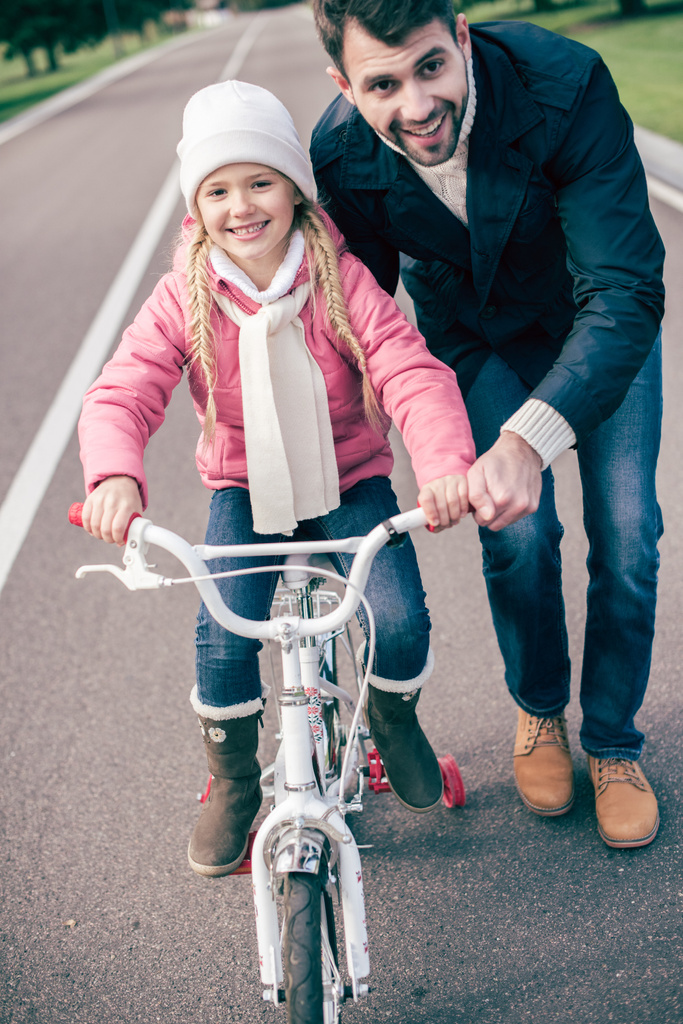 Apa biciklizni tanítja a lányát. - Fotó, kép