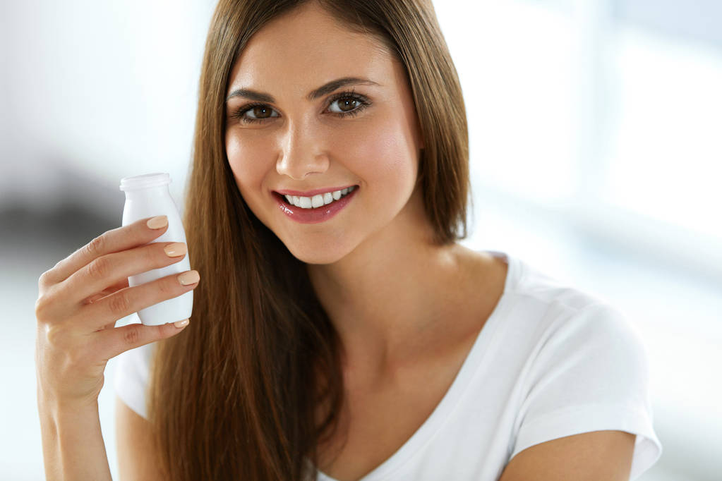 Nainen pitelee juomajogurttia sisätiloissa. Terveellinen ravitsemus
 - Valokuva, kuva