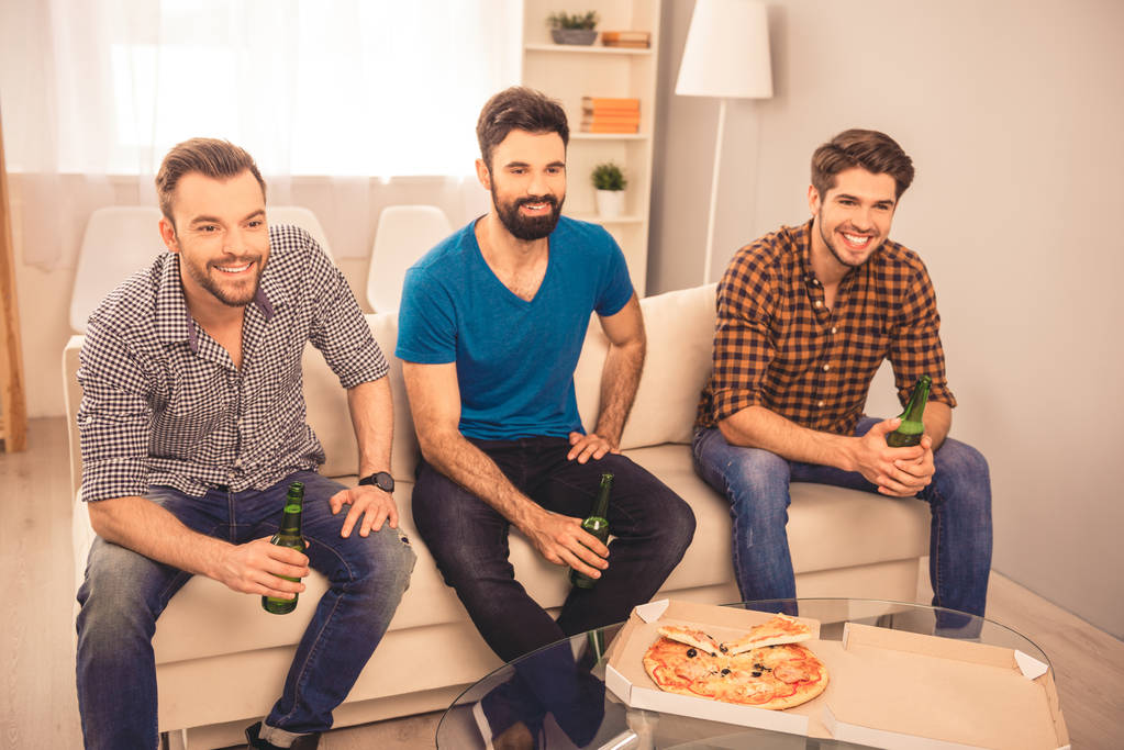 Portrait of handsome friends sitting on sofa with beer and pizza - Photo, Image