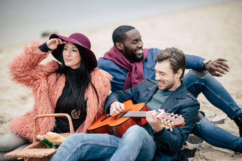 Szczęśliwy przyjaciół z gitarą na pikniku - Zdjęcie, obraz