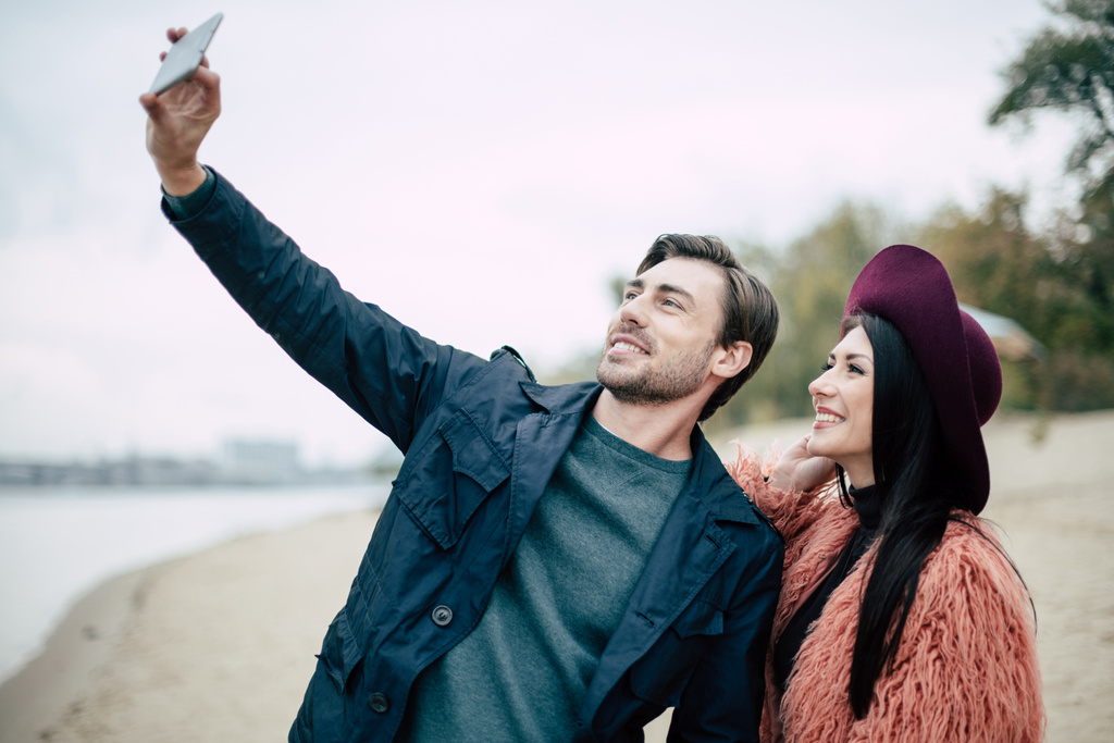 Sorrindo casal tomando selfie na praia
 - Foto, Imagem
